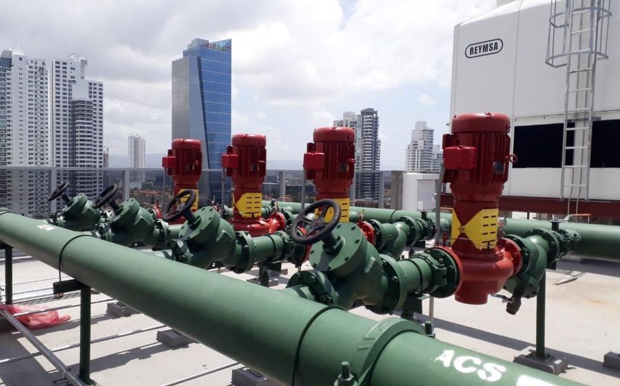 Rooftop chilled water pump manifold and cooling tower with the Panama City skyline behind