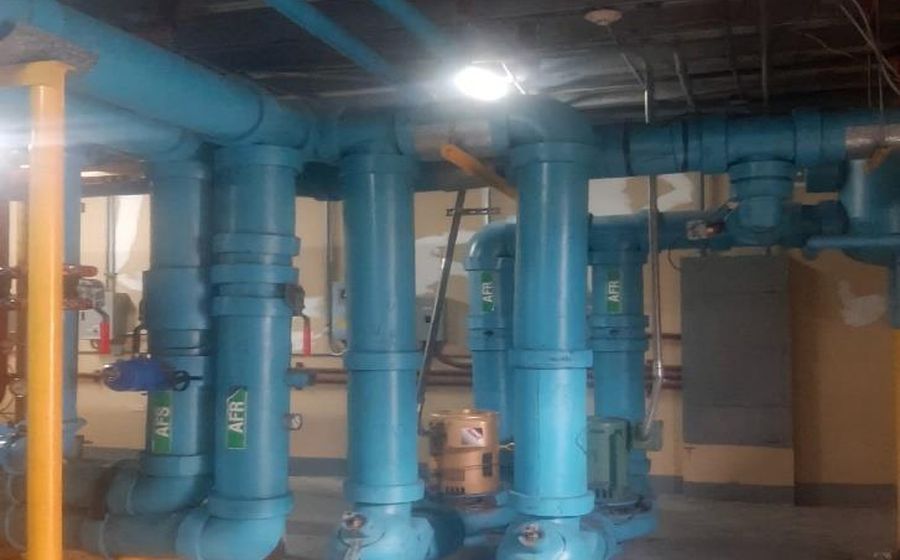 Chilled water distribution pipework and valve sets running through a plant room ceiling