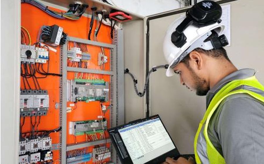 Technician commissioning a control panel with a laptop on site